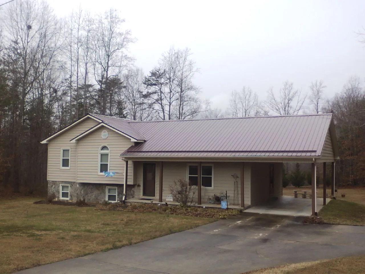 Burgundy metal roof on a tan split level home with an attached carport in Morgantown