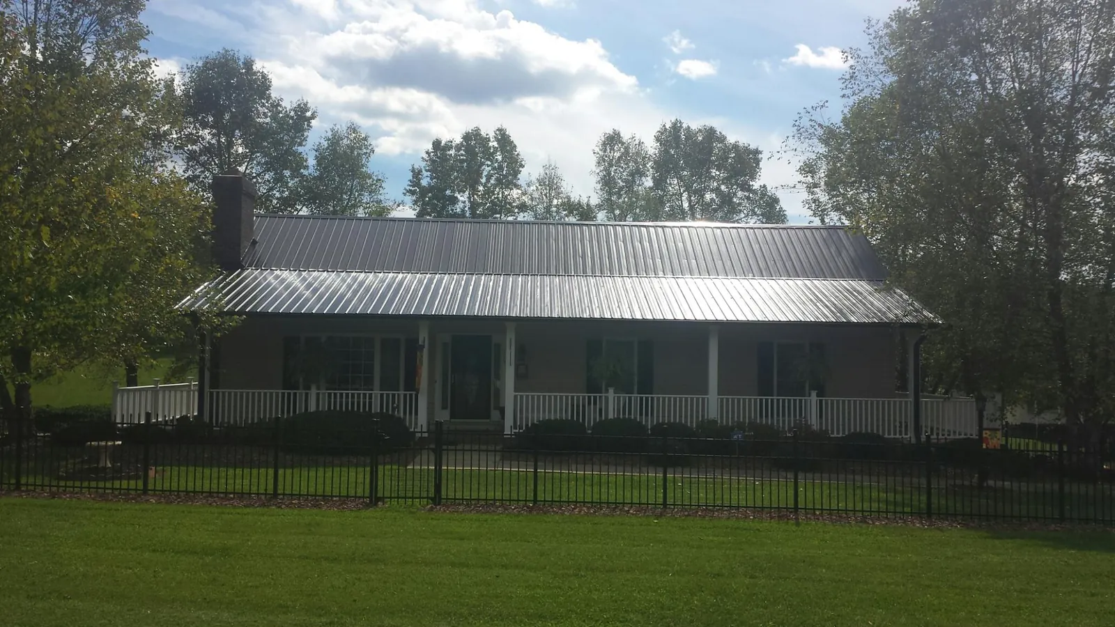 Gray metal roof on a brick ranch with a full width front porch — Gutter Guard Installation work by our crew in Morgantown