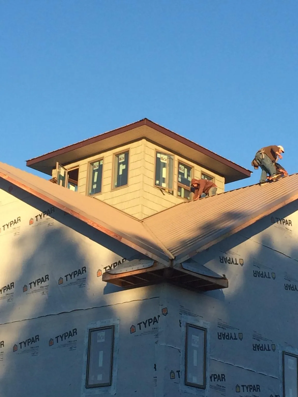 Roofers working around a rooftop cupola on a new metal roof at sunset — Roof Waterproofing in Morgantown by Roofing Brothers